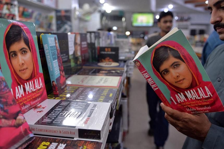 A Pakistani customer looks at the autobiography of Malala Yousafzai at a bookstore in Islamabad, Pakistan, on Oct 10, 2014. -- PHOTO: AFP