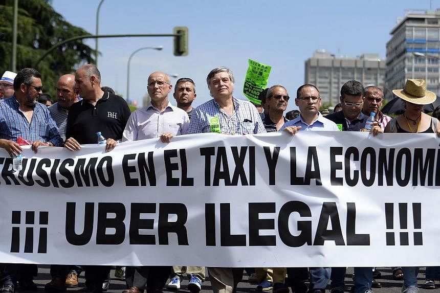 A file picture taken on June 11, 2014 shows taxi drivers carrying a banner during a strike action in protest of unlicensed taxi-type-services in central Madrid. A judge on Dec 9, 2014 banned the popular US cellphone-based taxi service Uber from opera