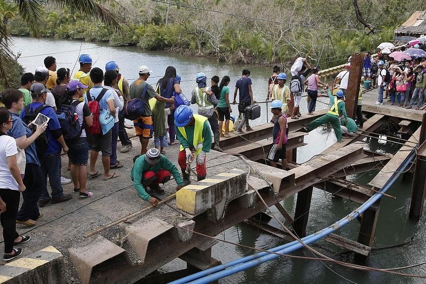 Residents cross a bridge, which was damaged by Typhoon Hagupit, in San Julian, Eastern Samar in central Philippines on Dec 10, 2014. -- PHOTO: REUTERS
