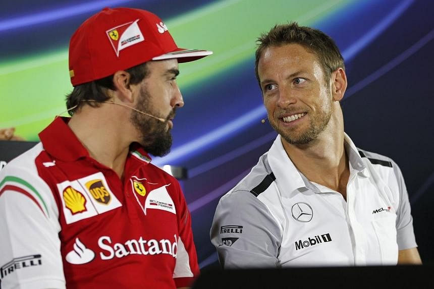 Ferrari Formula One driver Fernando Alonso of Spain (left) talks with McLaren Formula One driver Jenson Button of Britain during a news conference at the Yas Marina circuit, before the start of the Abu Dhabi Grand Prix on Nov 20, 2014.&nbsp;-- PHOTO: