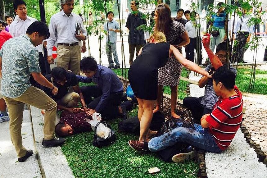 Members of the public attending to Indonesian businessman Kang Tie Tie, who&nbsp;was wounded in the abdomen and right arm in an armed robbery at Raffles Place on Nov 14, 2014. -- PHOTO: LEON LEE