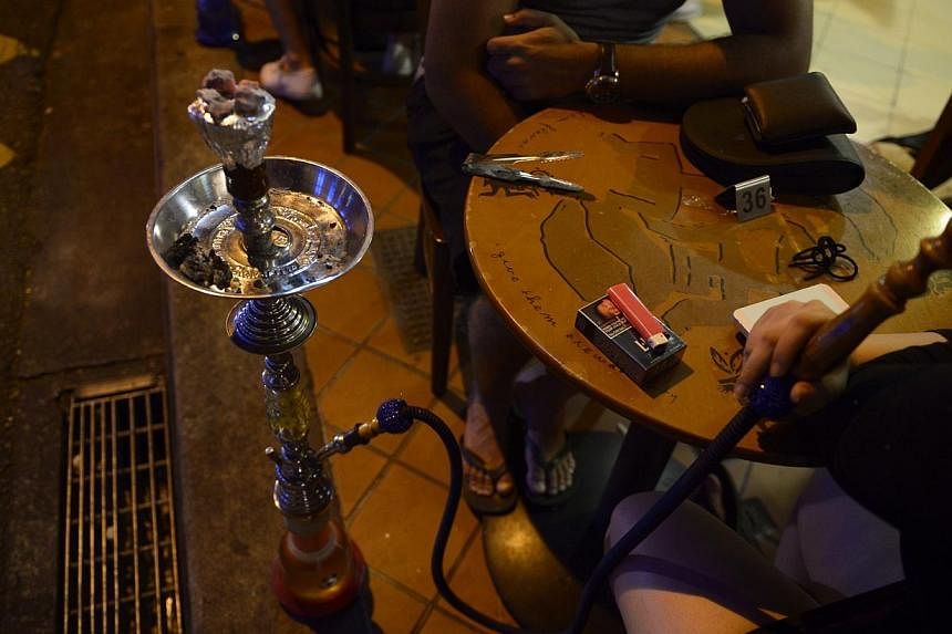 A customer smokes a shisha or "hookah" pipe at a cafe on Bussorah Street on Nov 4, 2014.&nbsp;Singapore appears to be alone in its ban on shisha, the sweet-smelling tobacco product that is smoked socially in several parts of the world. -- PHOTO: ST F