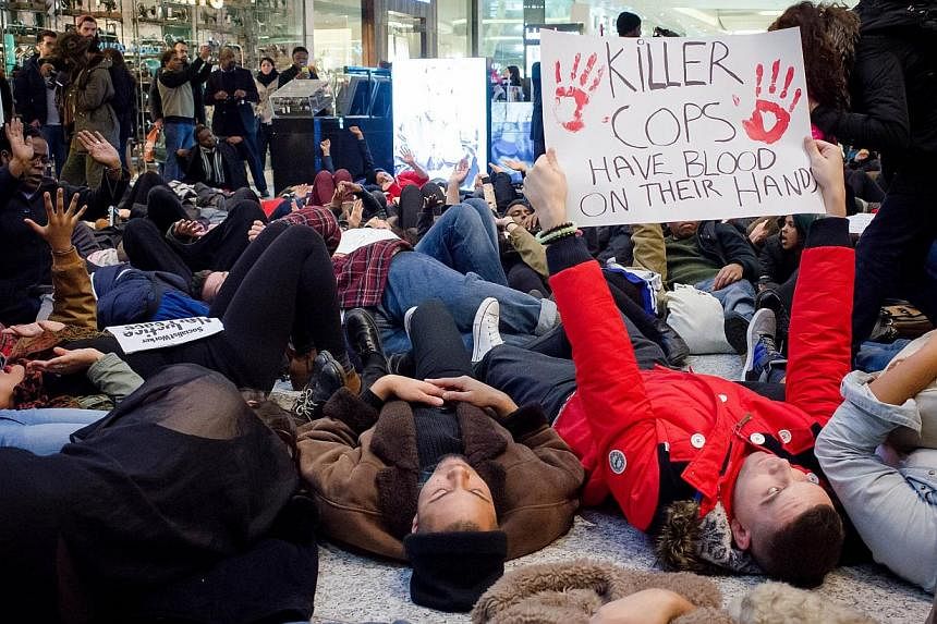 A group of protesters create a "die-in" at the Westfield shopping mall in West London on Dec 10, 2014, in support of protests in the US over the killings of black suspects by white police officers. -- PHOTO: AFP&nbsp;