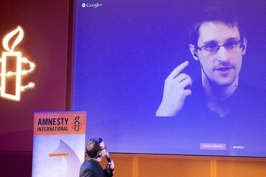 Former US National Security Agency contractor Edward Snowden, who is in Moscow, is seen on a giant screen during a live video conference for an interview as part of Amnesty International's annual Write for Rights campaign at the Gaite Lyrique in Pari