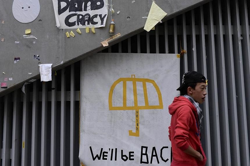 A man walks past banners displayed on a wall before police and bailiffs clear roads at the pro-democracy site in the Admiralty district in Hong Kong on Dec 11, 2014. -- PHOTO: AFP