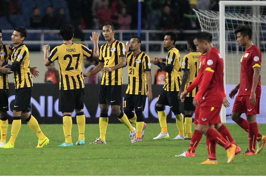 Malaysia's players (in yellow) celebrate their 4-2 victory over Vietnam after the second leg of their AFF Suzuki Cup 2014 semi-final second leg tie at the My Dinh stadium in Hanoi on Dec 11, 2014. -- PHOTO: REUTERS