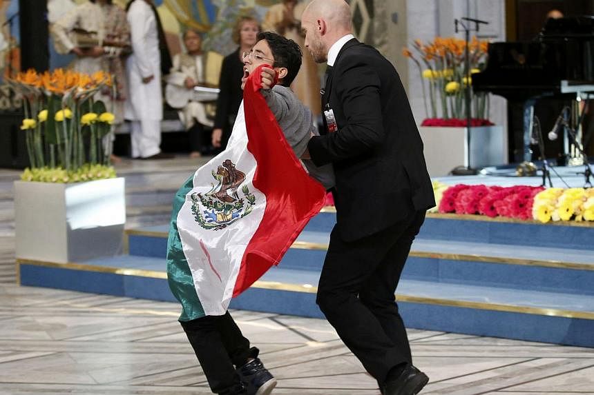 A security officer stops a young man with the flag of Mexico as he tried to approach Nobel Peace Prize laureates Malala Yousafzai and Kailash Satyarthi (unseen) during the Nobel Peace Prize awards ceremony at the City Hall in Oslo, Norway on Dec 10, 