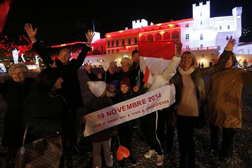 People celebrate in front of the Palace of Monaco as they celebrate the birth of baby twins to Prince Albert II and Princess Charlene of Monaco on Dec 10, 2014 in Monaco. -- PHOTO: AFP&nbsp;