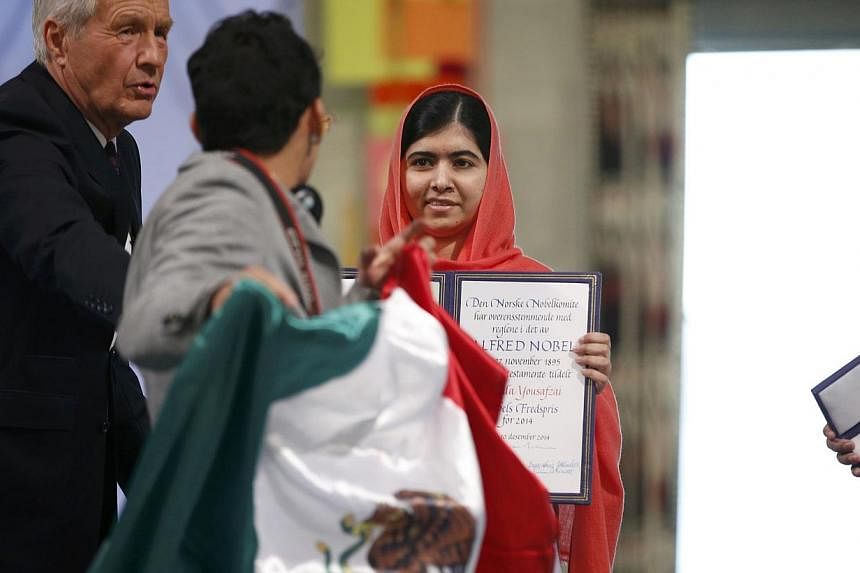 Chair of The Norwegian Nobel Committee, Thorbjorn Jagland (left) tries to stop a young man with a Mexican flag from approaching Nobel Peace Prize laureate Malala Yousafzai during the Nobel Peace Prize awards ceremony at the City Hall in Oslo Dec 10, 