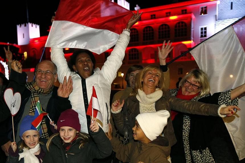People celebrate in front of the Palace of Monaco as they celebrate the birth of baby twins to Prince Albert II and Princess Charlene of Monaco on Dec 10, 2014 in Monaco. Prince Albert II of Monaco and his wife Charlene welcomed their twin babies Gab
