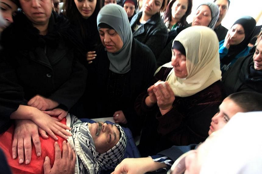 Relatives of senior Palestinian official Ziad Abu Ein mourn over his body before the funeral in the West Bank city of Ramallah on Dec 11, 2014. -- PHOTO: AFP