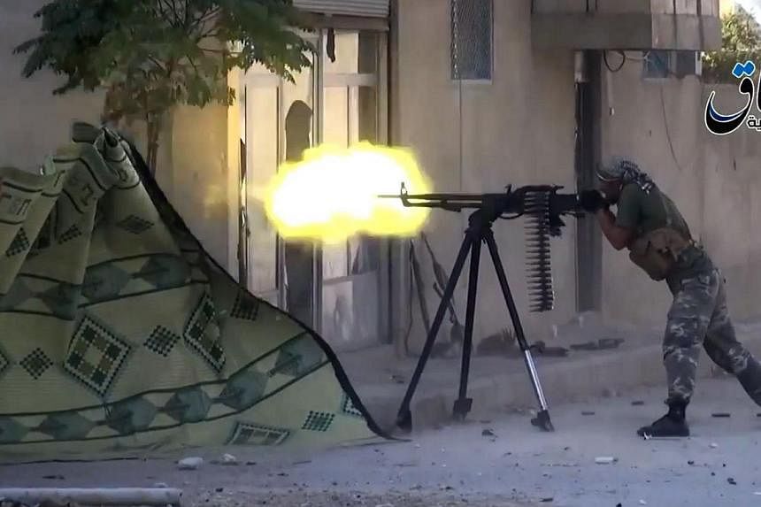 An image grab taken from a video uploaded on October 11, 2014 by Aamaq News Agency, a Youtube channel which posts videos from areas under the Islamic State (IS) group's control, allegedly shows an Islamic State group fighter firing a heavy machine gu