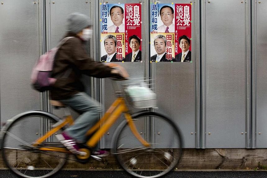 A man cycles past election posters ahead of Japan's upcoming snap election in Tokyo on Dec 11, 2014. -- PHOTO: REUTERS&nbsp;