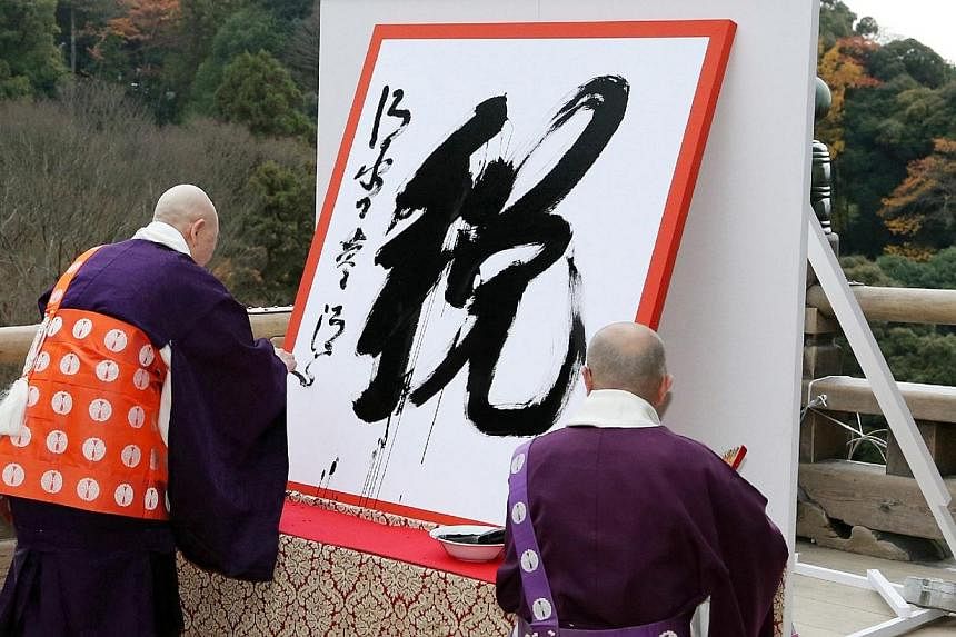 Seihan Mori (left), the chief priest of Kiyomizu temple, displays his caligraphy of a kanji (or Chinese character),"zei" meaning tax which was chosen as the single best Chinese character symbolizing this year's national ethos in Japan at the Buddhist