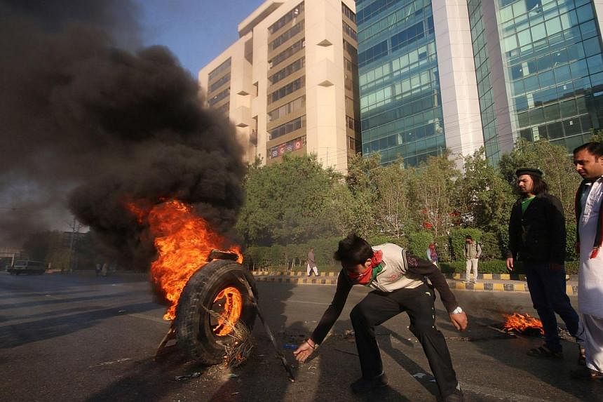 Activists of Imran Khan's Pakistan Tehreek-e-Insaaf (PTI) party burn tyres on a street during a protest in Karachi on Dec 12, 2014.&nbsp;The latest round of protests against the Pakistani government led by cricketer-turned-politician Imran Khan disru