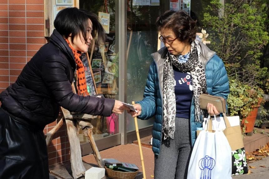 Ms Mizuho Nakayama (left), a member of the "Ikareru Joshikai" (The Angry Girls Group) gives a flyer of an opposition candidate to a female voter for the Dec 14, 2014 general election in Tokyo, on Dec 12. -- PHOTO: AFP