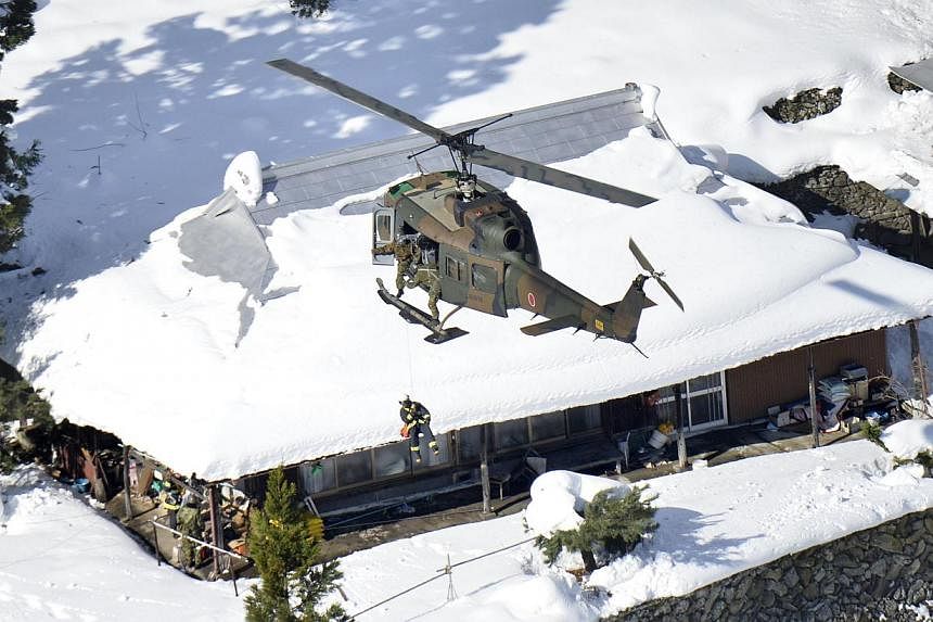 Japan Self-Defense Forces' rescue workers try to confirm the safety of residents as its helicopter hovers above a community in Tsurugi, which is isolated following a heavy snow, in Tokushima Prefecture on Dec 8, 2014, in this photo taken by Kyodo. --