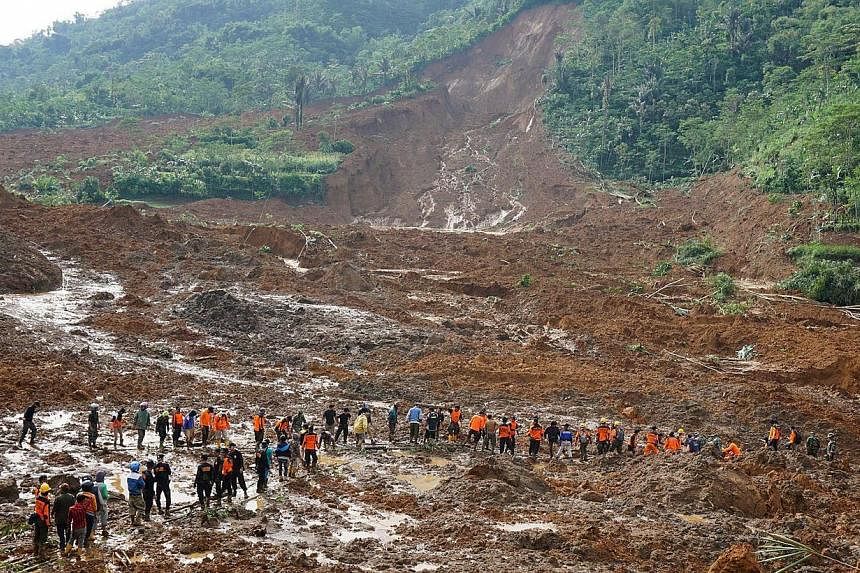 A rescue team remove victims bodies of a landslide triggered by torrential downpours at Jemblung village in Banjarnegara, Central Java province on Dec 13, 2014. -- PHOTO: AFP&nbsp;