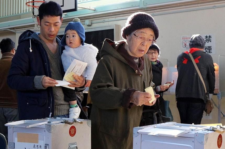 Voters cast votes in Japan's general election at a polling station in Tokyo on Dec 14, 2014.&nbsp;Millions of Japanese are braving wintry weather to vote in a snap election on Sunday that will enable Prime Minister Shinzo Abe to claim a fresh mandate