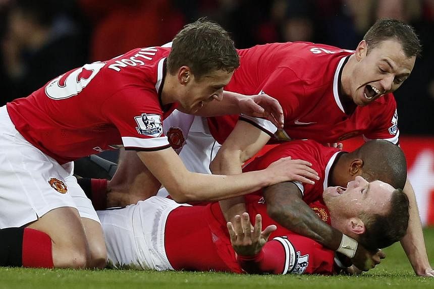 Manchester United's Wayne Rooney (on ground) celebrates with Michael Carrick (left), Jonny Evans (right) and Ashley Young (partially obscured), after scoring the opening goal during their English Premier League football match against Liverpool at Old