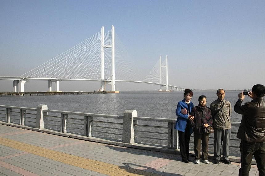People pose for pictures with the new Friendship Bridge over the Yalu River, connecting China's Dandong and North Korea's Sinuiju, on Nov 9, 2014.&nbsp;North Korea on Sunday, Dec 14, put on display an American who had apparently entered the country i