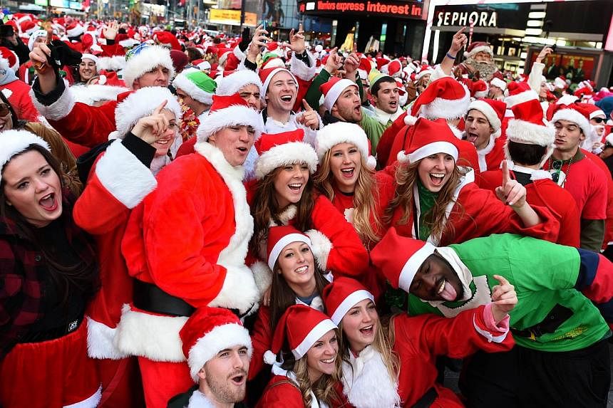 People dressed as Santa Claus and Mrs Claus pose in Times Square as they gather for the annual Santacon festivities on Dec 13, 2014 in New York. -- PHOTO: AFP