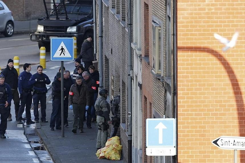 Belgian police officers and special forces stand at the entrance of a building, where four gunmen have taken a man hostage, in Ghent on Dec 15, 2014. -- PHOTO: REUTERS