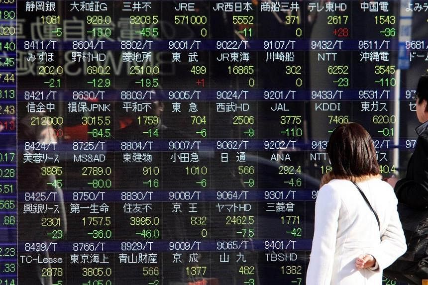 Pedestrians gaze at a share prices board in Tokyo on Dec 15, 2014.&nbsp;Japan's Nikkei share average fell 1.6 per cent, drawing little momentum from Japanese Prime Minister Shinzo Abe's big election victory on Sunday, which was a boost for his reflat