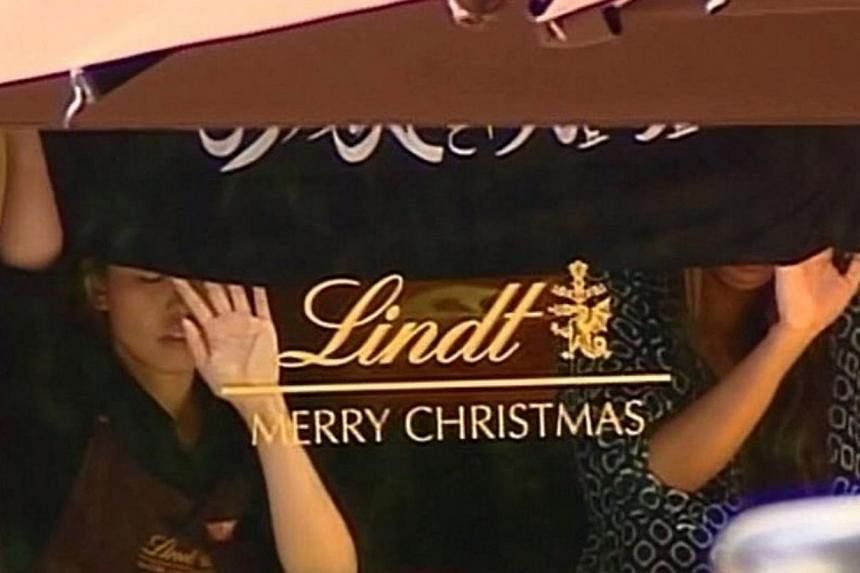 This screengrab taken from the Australian Channel Seven broadcast shows presumed hostages holding up a flag with Arabic writing inside a cafe in the central business district of Sydney on Dec 15, 2014.&nbsp;A man holding hostages in a Sydney cafe on 