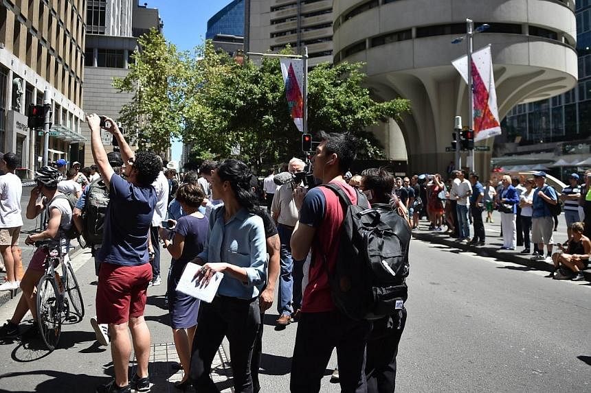 Journalists and onlookers gather in Martin Place in the central business district of Sydney on Dec 15, 2014.&nbsp;A hostage situation at a cafe in downtown Sydney, Australia, has rocked the country, but its people have found a way to stand as one. --