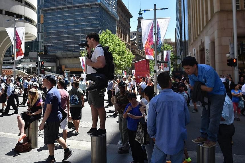Journalists and onlookers gather in Martin Place in the central business district of Sydney on Dec 15, 2014.&nbsp;Australian police said on Monday they are monitoring alleged demands made on social media by hostages being held in a siege at a Sydney 