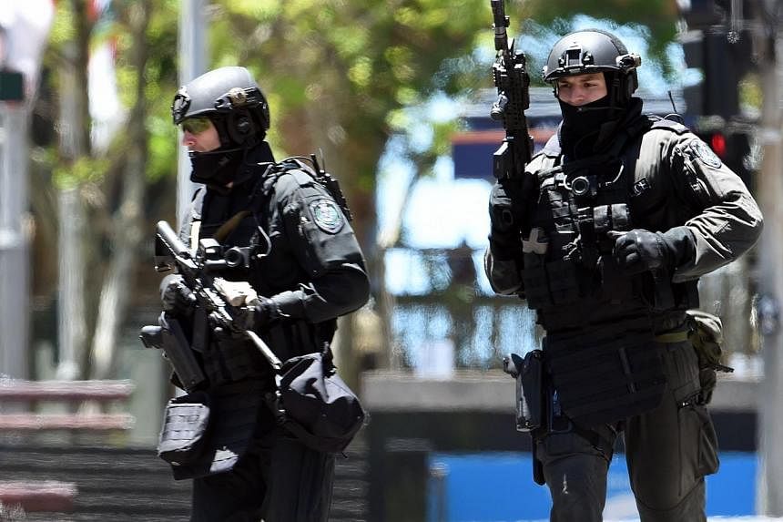 Armed police are seen outside a cafe in the central business district of Sydney on Dec 15, 2014.&nbsp;-- PHOTO: AFP&nbsp;