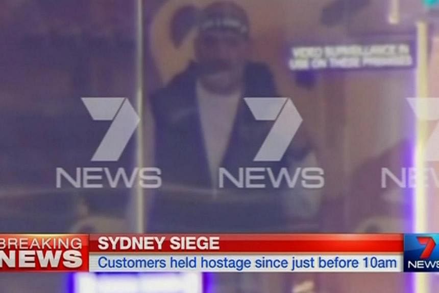 A man is seen standing behind the window of the Lindt cafe, where hostages are being held, in this still image taken from video from Australia's Seven Network on Dec 15, 2014. -- PHOTO: REUTERS