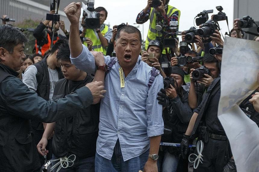 Tycoon and Apple Daily Newspaper owner Jimmy Lai shouts slogan before he is taken away by police officer at an area previously blocked by pro-democracy supporters, outside the government headquarters in Hong Kong on Dec 11, 2014. -- PHOTO: REUTERS