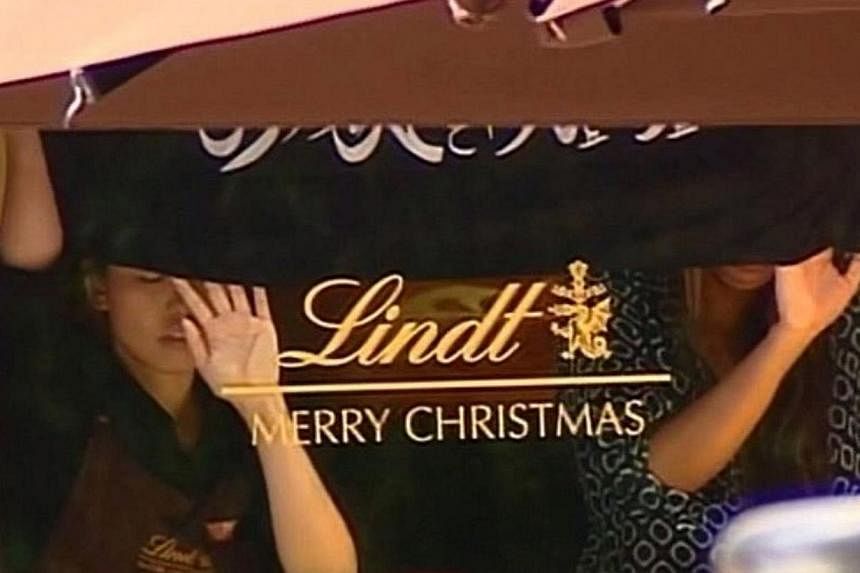 This screengrab taken from the Australian Channel 7 broadcast shows presumed hostages holding up a flag with Arabic writing inside a cafe in the central business district of Sydney on Dec 15, 2014. -- PHOTO: AFP