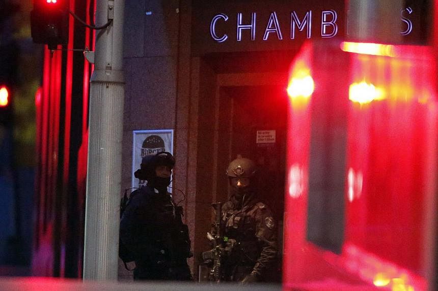 Heavily armed policemen stand guard outside the building containing the Lindt cafe, where hostages are being held, at Martin Place in central Sydney on Dec 15, 2014. -- PHOTO: REUTERS