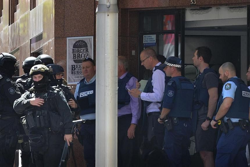 Armed police are seen outside a cafe in the central business district of Sydney on Dec 15, 2014. Hostages were being held inside a cafe in central Sydney with an Islamic flag displayed against a window, according to witnesses and reports, while polic
