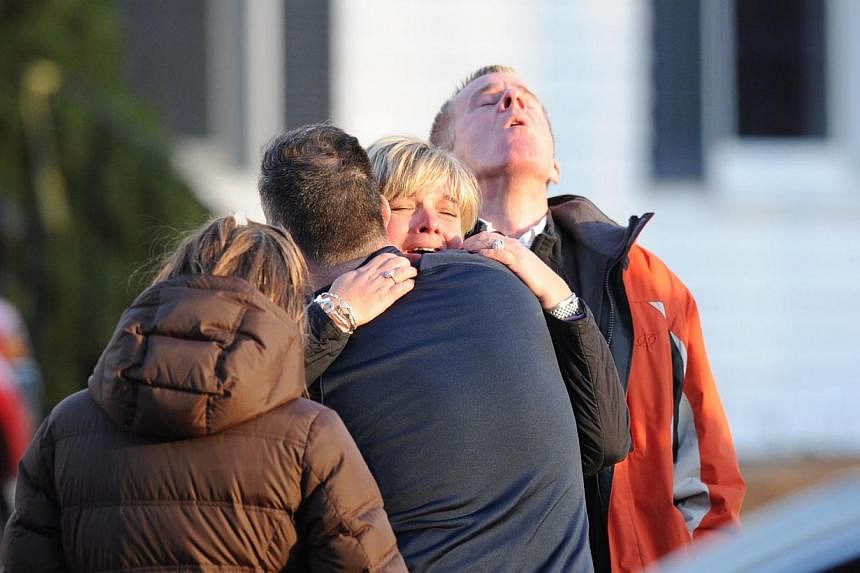 Unidentified people embrace December 14, 2012, at the scene from the aftermath of a school shooting at an elementary school in Newtown, Connecticut that brought police swarming into the leafy neighborhood, while other area schools were put under lock