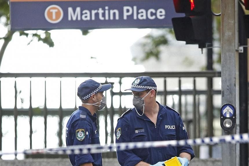 New South Wales police officers wear protective masks as they place marker cones over potential evidence in their investigation into the Sydney cafe siege, on Tuesday, Dec 16, 2014.&nbsp;The Asian Football Confederation said on Tuesday that it had as