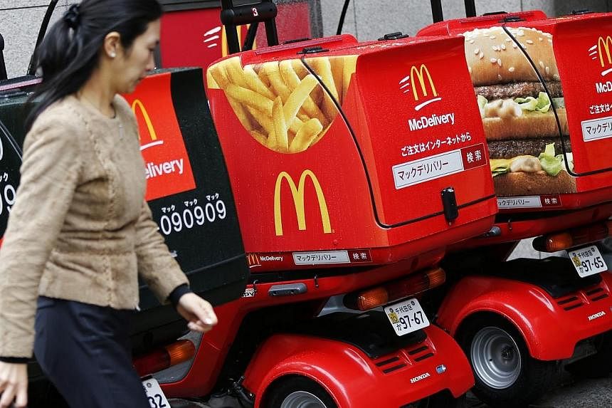 A woman walks past delivery scooters decorated with pictures of McDonald's food, including a packet of fries and a Big Mac burger, outside a McDonald's store in Tokyo on Dec 16, 2014. -- PHOTO: REUTERS