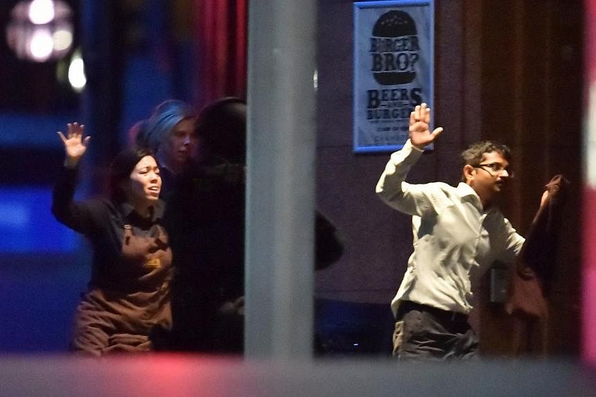Hostages run out of a cafe in the central business district of Sydney on Dec 16, 2014.Ms Harriette Denny (left) was able to escape just minutes before the siege ended in gunfire on Tuesday. -- PHOTO: AFP
