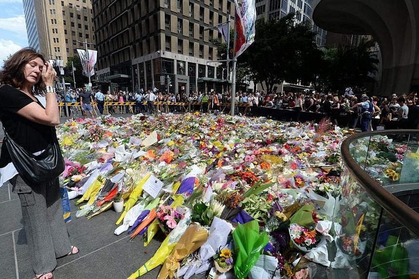 A visitor looks at a makeshift memorial near the scene of a fatal siege in the heart of Sydney's financial district on Dec 16, 2014.&nbsp;-- PHOTO: AFP