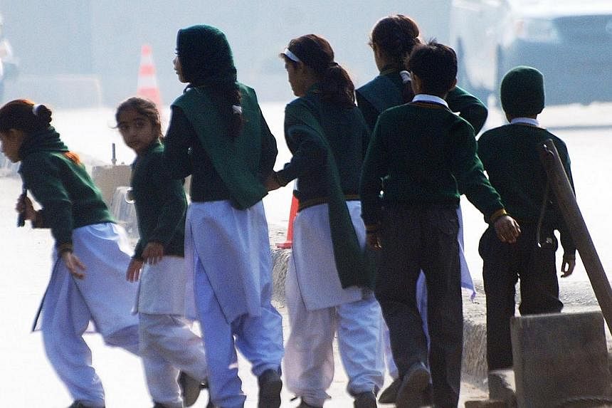 Schoolchildren cross a road as they move away from a military run school that is under attack by Taleban gunmen in Peshawar on Dec 16, 2014. -- PHOTO: AFP