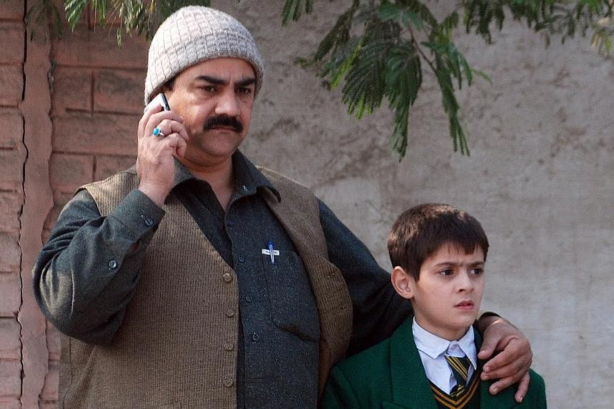 A man talks on a phone, with his arm around a student, outside a military run school that is under attack by Taleban gunmen in Peshawar, on Dec 16, 2014. -- PHOTO: REUTERS