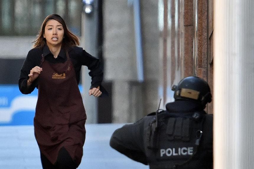 Ms Bae's fellow worker Elly Chen runs towards police from Sydney's Lindt cafe on Dec 15, 2014. -- PHOTO: AFP
