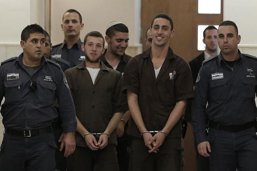 Three Israeli suspects, members of the right-wing Lehava organisation, are escorted by security to a hearing at the District Court in Jerusalem on Dec 15, 2014. -- PHOTO: AFP