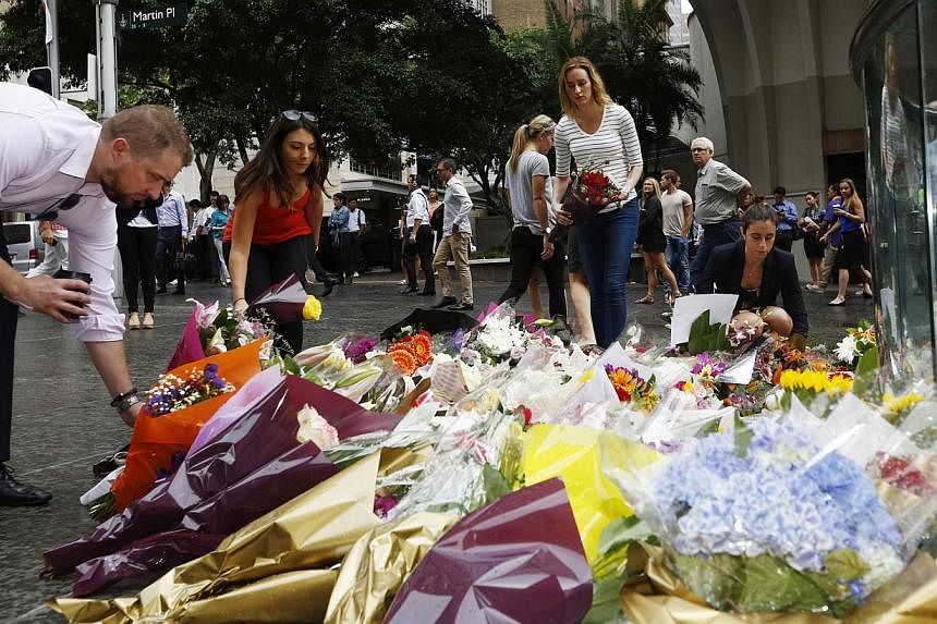 Mourners lay floral tributes to those who died in the Sydney cafe siege, near the site of the incident, in Martin Place. -- PHOTO: REUTERS