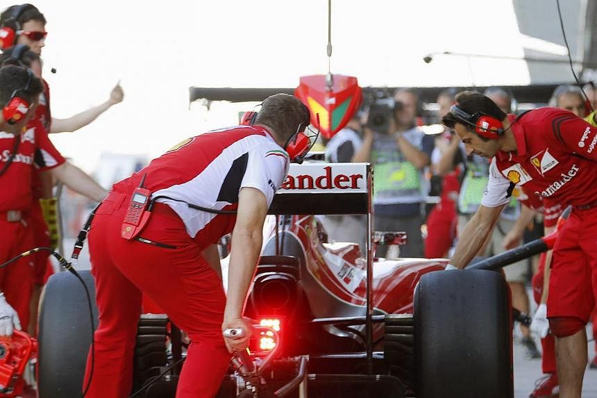 Mechanics lift Ferrari driver Fernando Alonso's car during the third practice session of the Abu Dhabi Grand Prix. -- PHOTO: REUTERS
