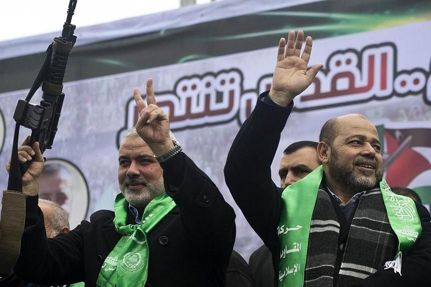 Gaza Hamas leaders Ismail Haniya (left) and Mussa Abu Marzuq brandish a weapon as they greet supporters during a parade marking the 27th anniversary of the Islamist movement’s creation on Dec 14, 2014 in Gaza City. The Palestinian Islamic militant 