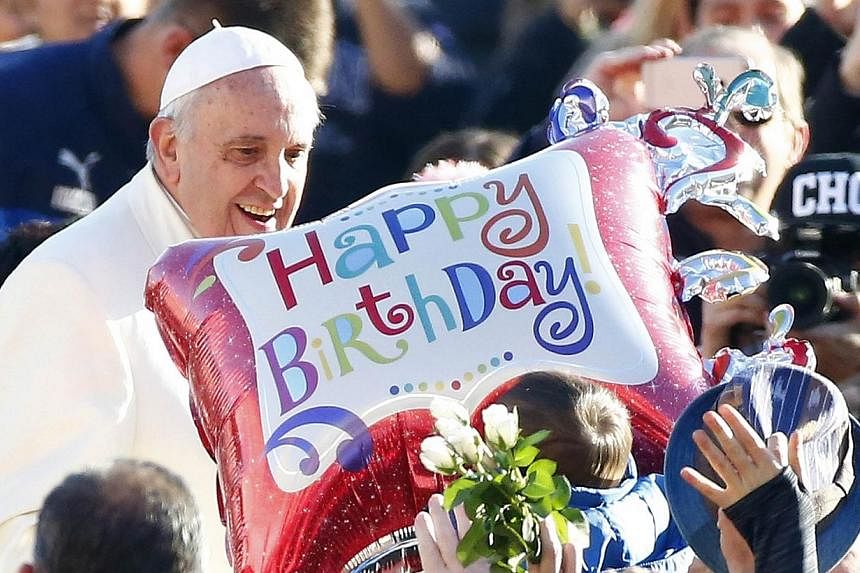 A supplicant holds a balloon as Pope Francis, whose 78th birthday is today, arrives to lead his general audience at the Vatican on Dec 17, 2014.&nbsp;Thousands of people sang "Happy Birthday" and danced a mass tango on Wednesday to celebrate the birt